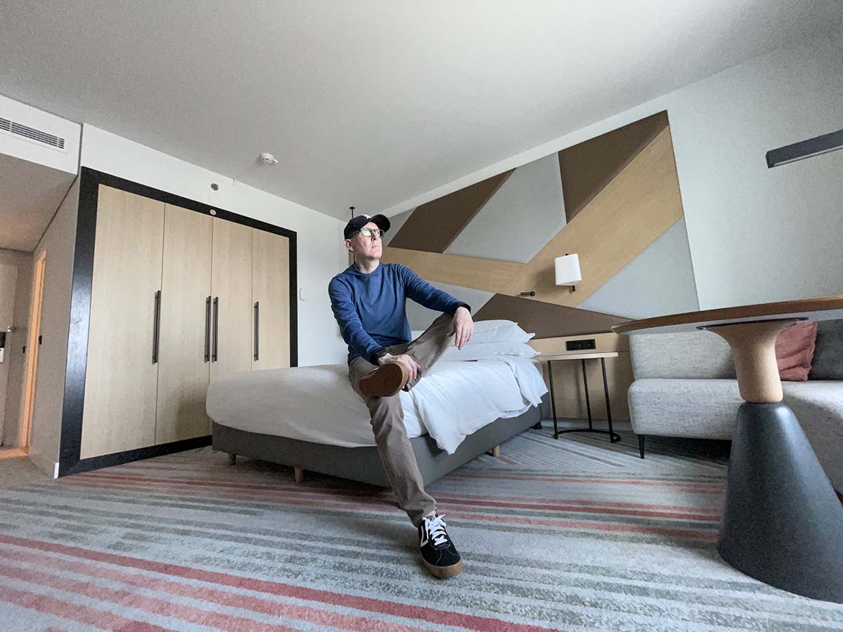 Scott sitting on the bed and looking out the window from his room at the Sheraton Hotel Schiphol Airport 