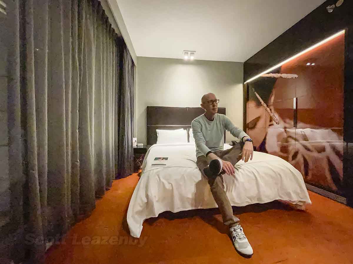 Scott Leazenby sitting on bed in park plaza hotel London