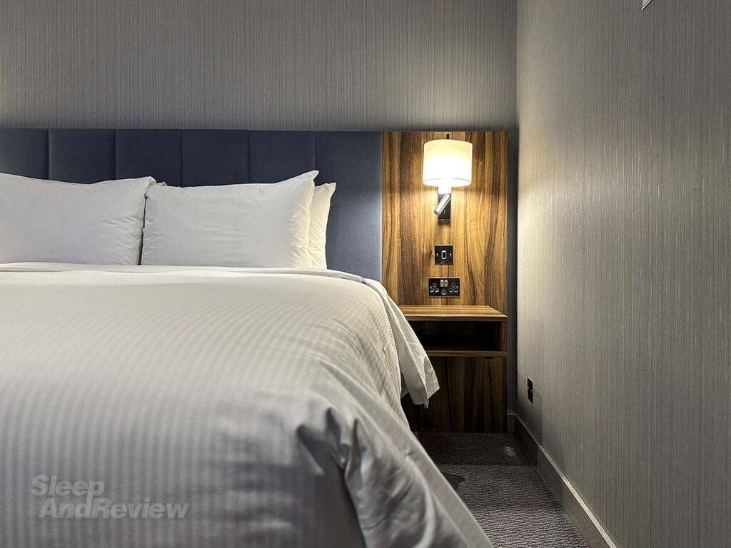 Bedside table with phone and electrical outlets in my room at the Hilton Garden Inn Heathrow Airport