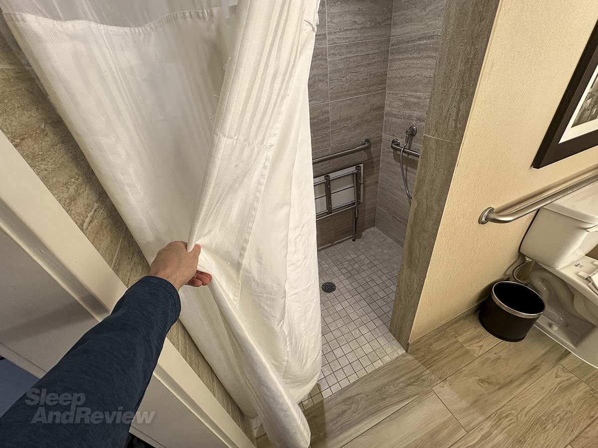 Opening the shower curtain leading to the walk-in shower in my bathroom at the Inverness Denver hotel